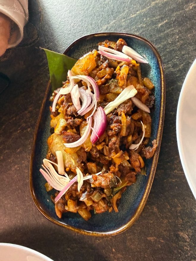 Stir-fried meat with coconut and onion rings on a banana leaf