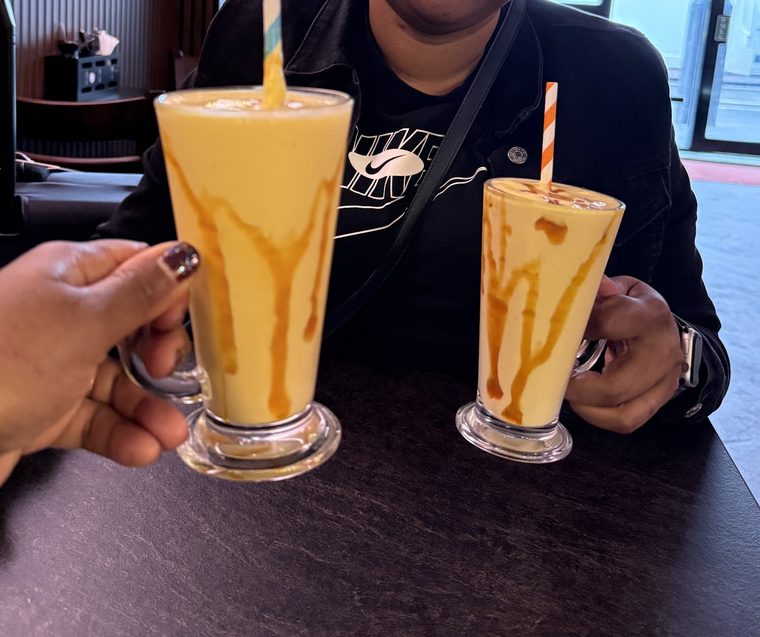Two tall glasses of mango lassi at the table